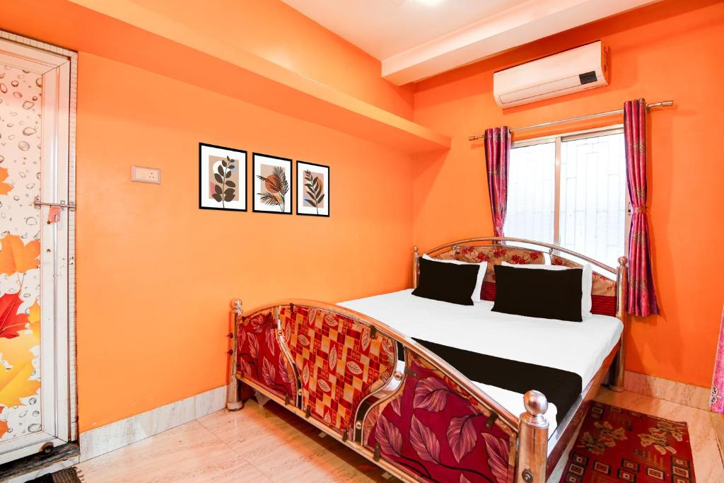um quarto com um quarto laranja com uma cama e uma janela em Hotel O A R Lodge em Durgāpur