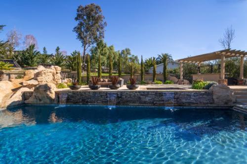 een zwembad in een tuin met een stenen muur bij A Villa with extraordinary views in Solvang