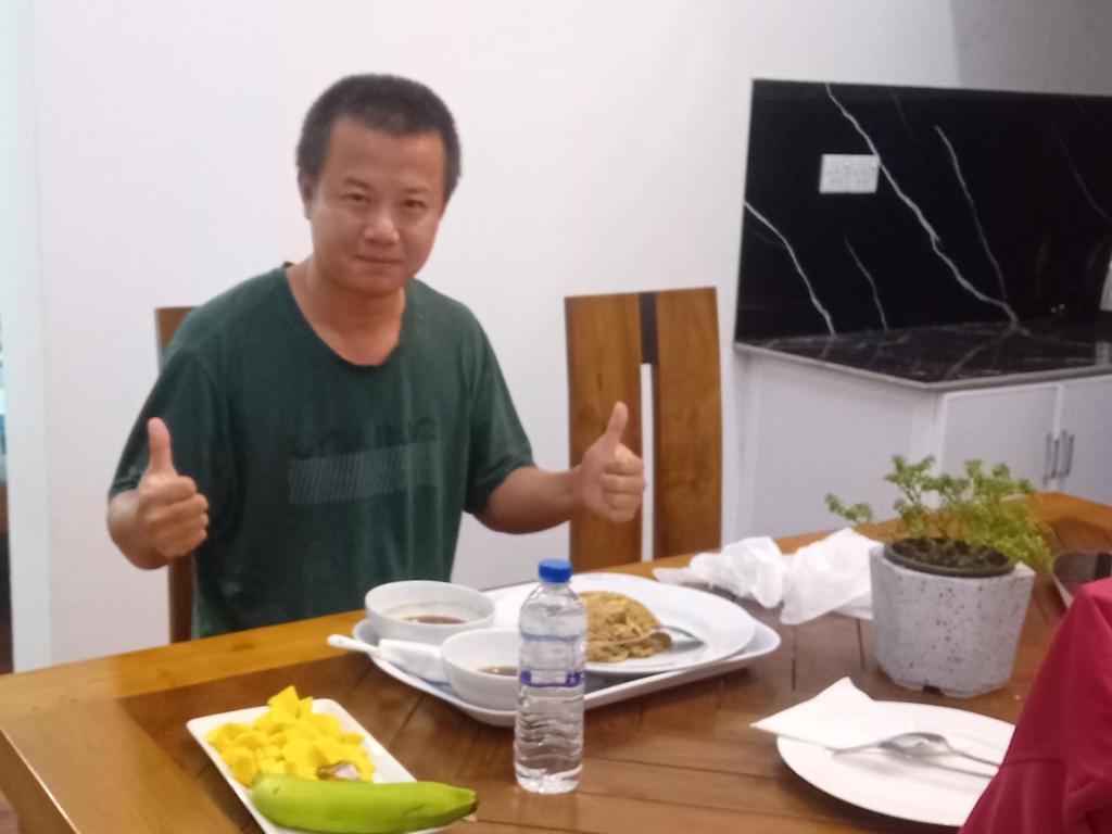a man giving thumbs up at a table with a plate of food at Mollusca Beach Villa in Waskaduwa