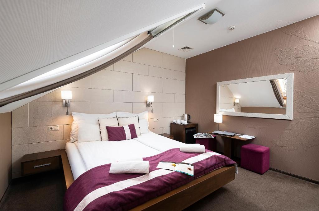 a bedroom with a large bed and a mirror at Hotel Fürdőház in Nyíregyháza