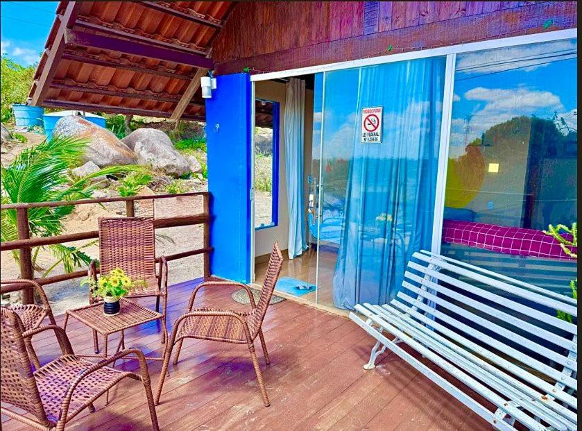 a porch with chairs and a bench and a table at Chalé Sun Happy in Serra de São Bento