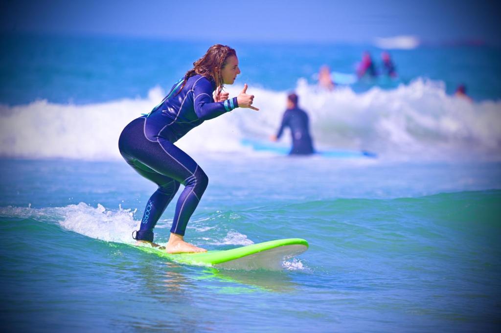 a woman riding a wave on a surfboard in the ocean at Adar surf house in Taghazout