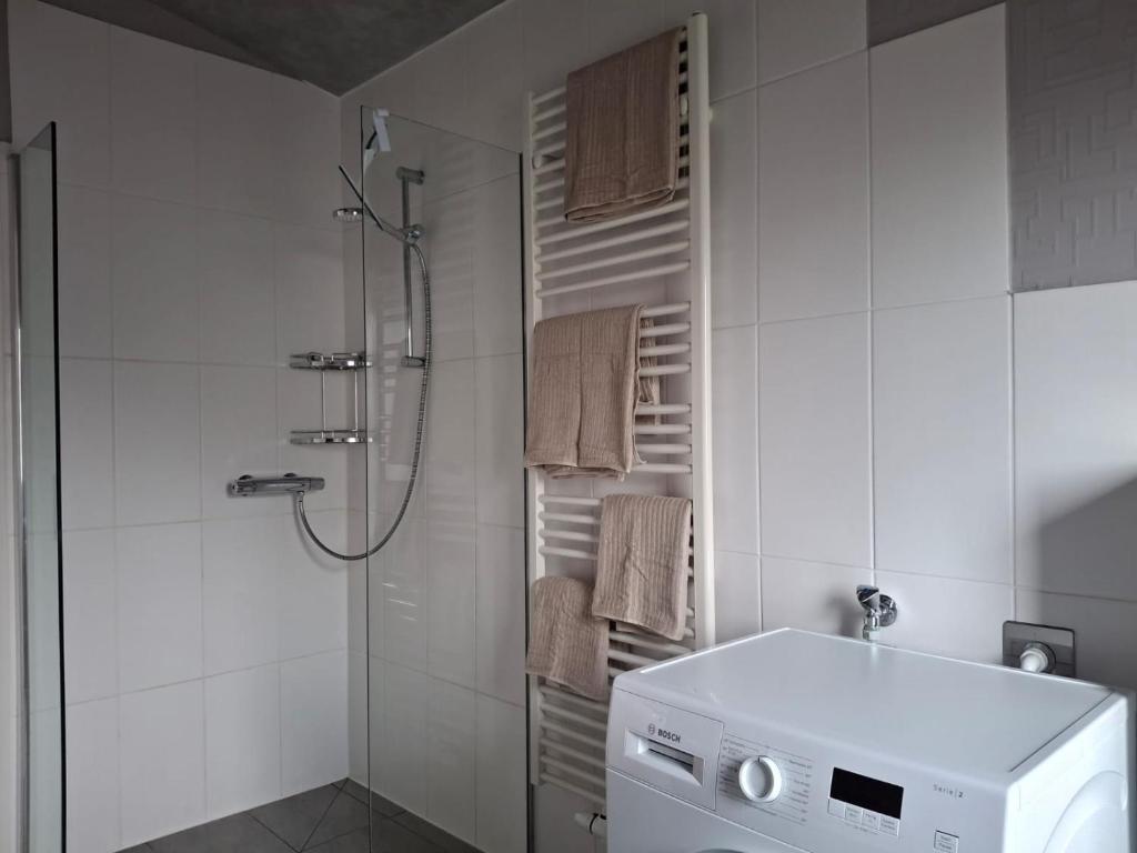 La salle de bains blanche est pourvue d'une douche et d'un lave-linge. dans l'établissement Ferienwohnung 2, à Northeim