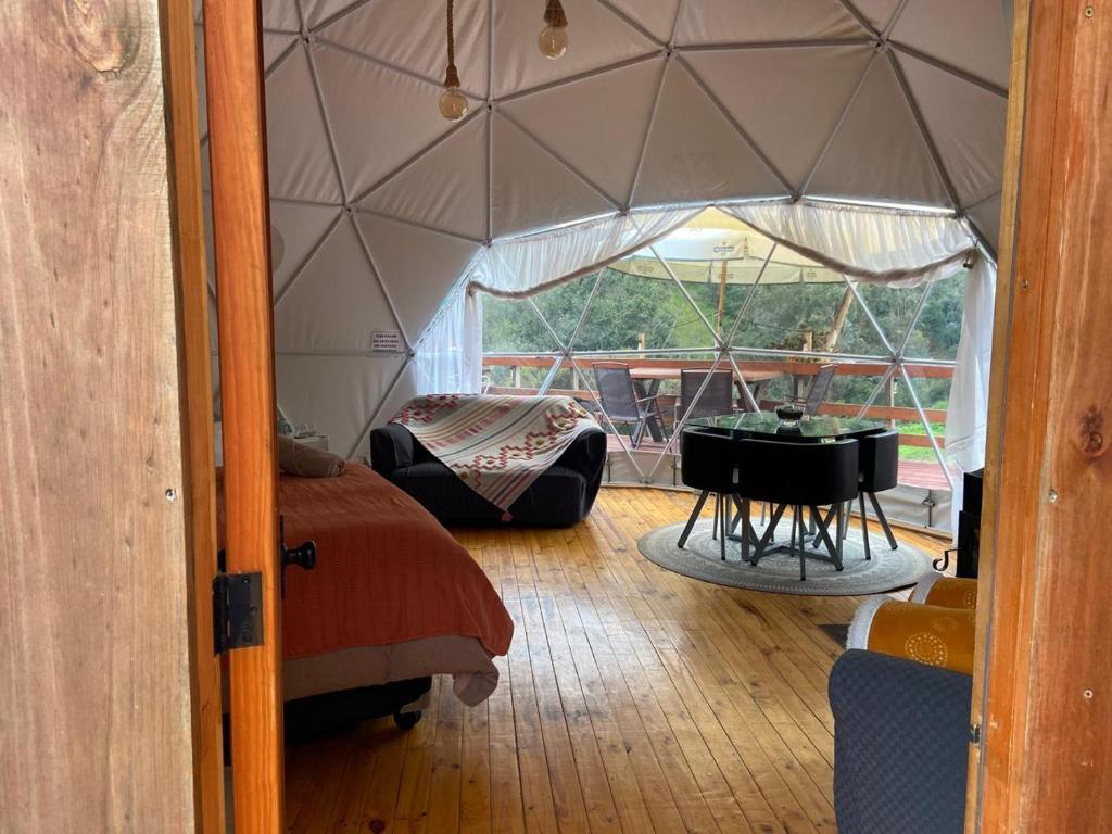 Una habitación con una cama y un piano en una tienda de campaña. en Domo con Hot Tub Piscina Sauna Olmue, en Olmué