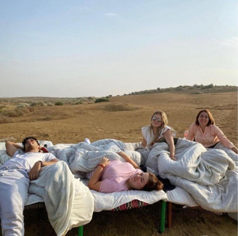 ジャイサルメールにあるDesert hostel Camp Sam Sand Dunes Jaisalmerの田んぼに横たわっている人々