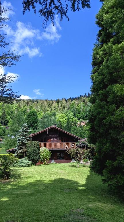 a house in the middle of a field with trees at Chalet du Grand Arbre in Le Ménil