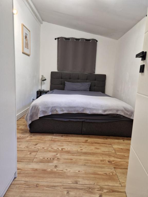 a bedroom with a large bed and a wooden floor at Green Hill Apartment in Birkenau