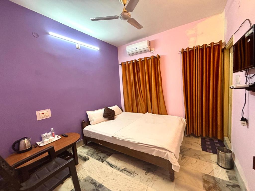 a bedroom with a bed and a table and a ceiling fan at Aryan guest house in Bodh Gaya