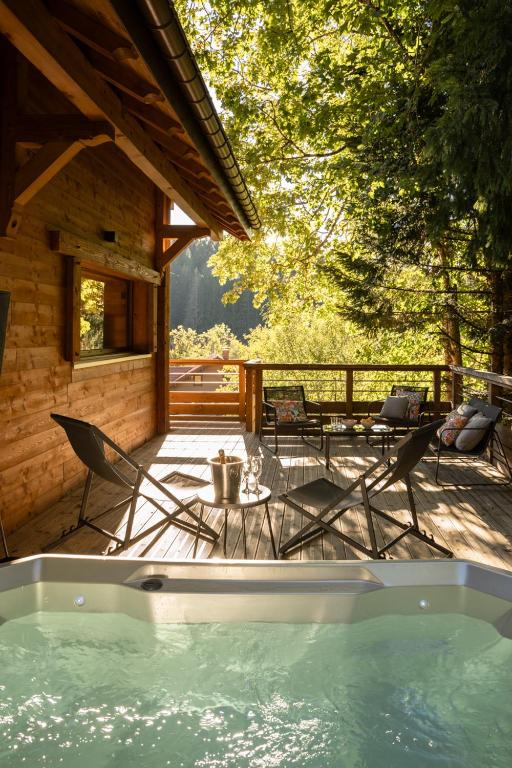a hot tub on a deck next to a cabin at Chalet Les Cimes - Sauna - Jacuzzi in Gérardmer