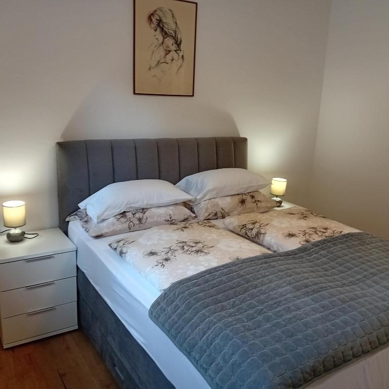 a bed in a bedroom with two lamps on a night stand at Apartman Andrić in Lovran