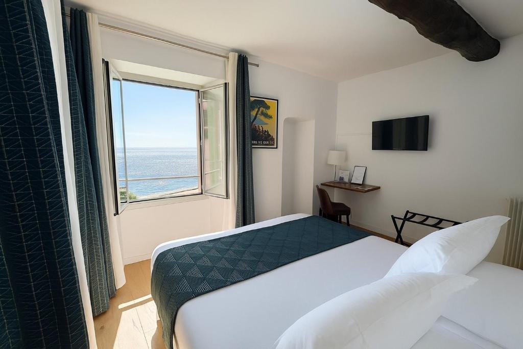 a bedroom with a bed and a window with the ocean at Hôtel Posta Vecchia in Bastia