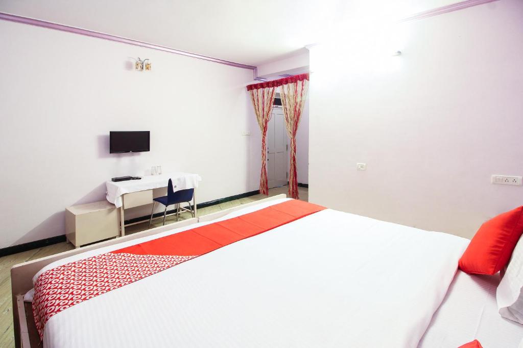 a bedroom with a bed and a desk and a tv at Hotel O Kingston Residency in Vānivilāsa Puram