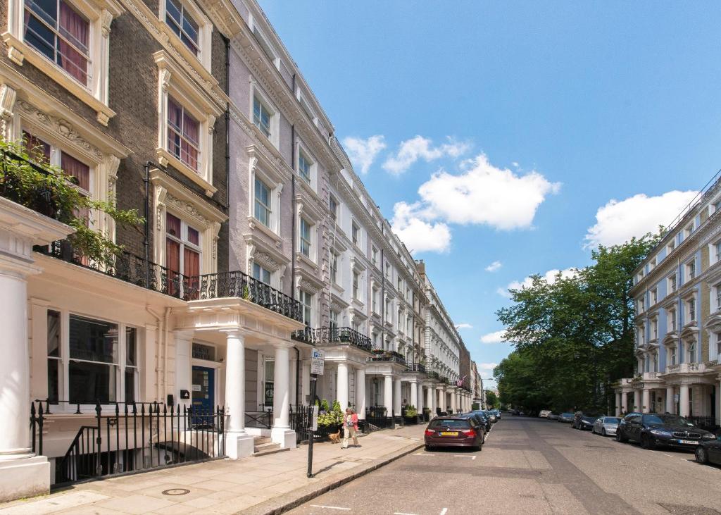 una calle con edificios y coches estacionados en la calle en Astor Kensington Hostel, en Londres