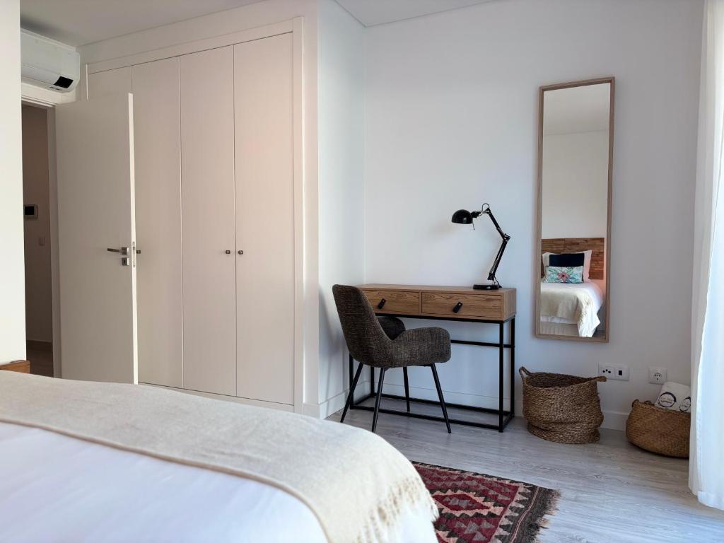 ein Schlafzimmer mit einem Bett, einem Schreibtisch und einem Stuhl in der Unterkunft Alto Mar Apartment in Peniche