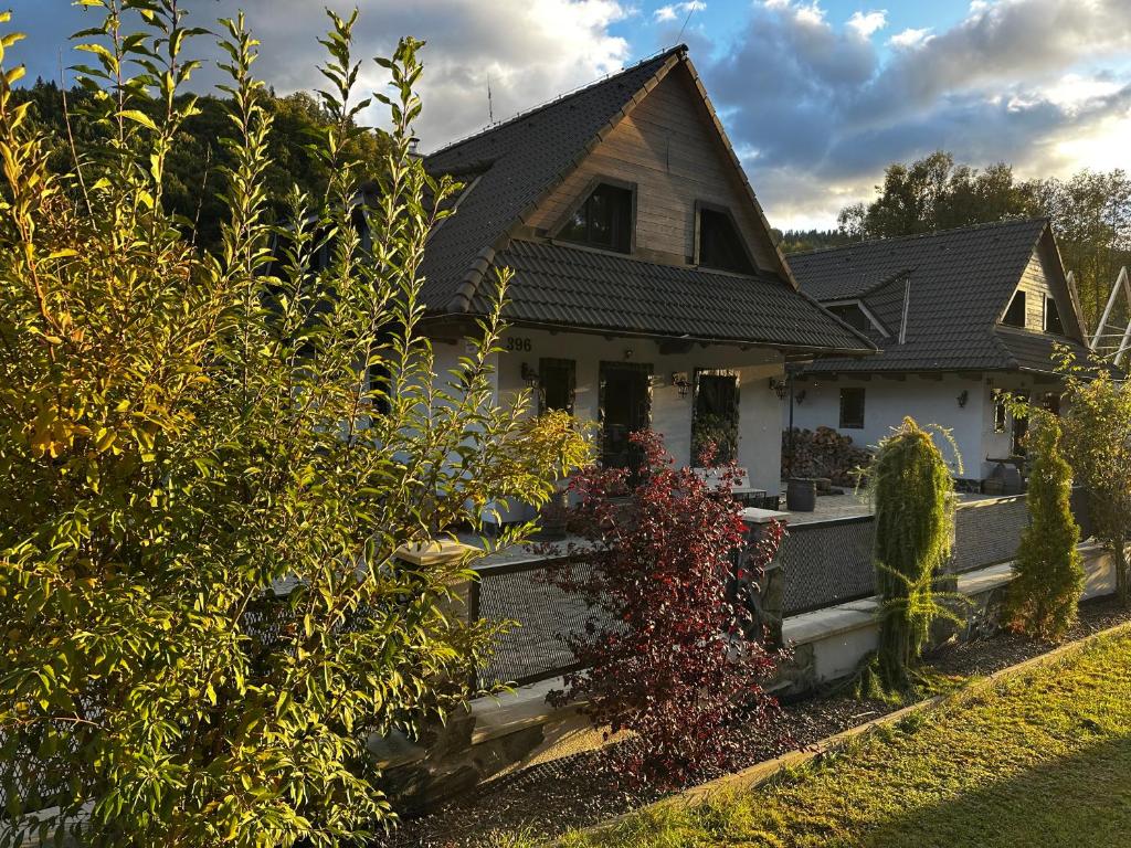 una casa blanca con techo negro y algunos arbustos en Tri chalúpky na Mýte, en Mýto pod Ďumbierom
