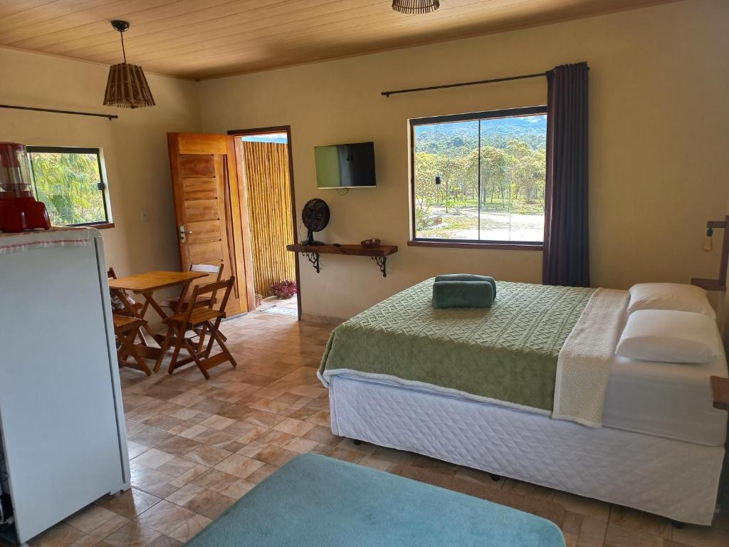 Un dormitorio con una cama y una mesa y una ventana. en Recanto Cachoeiras de Ibicoara, en Ibicoara