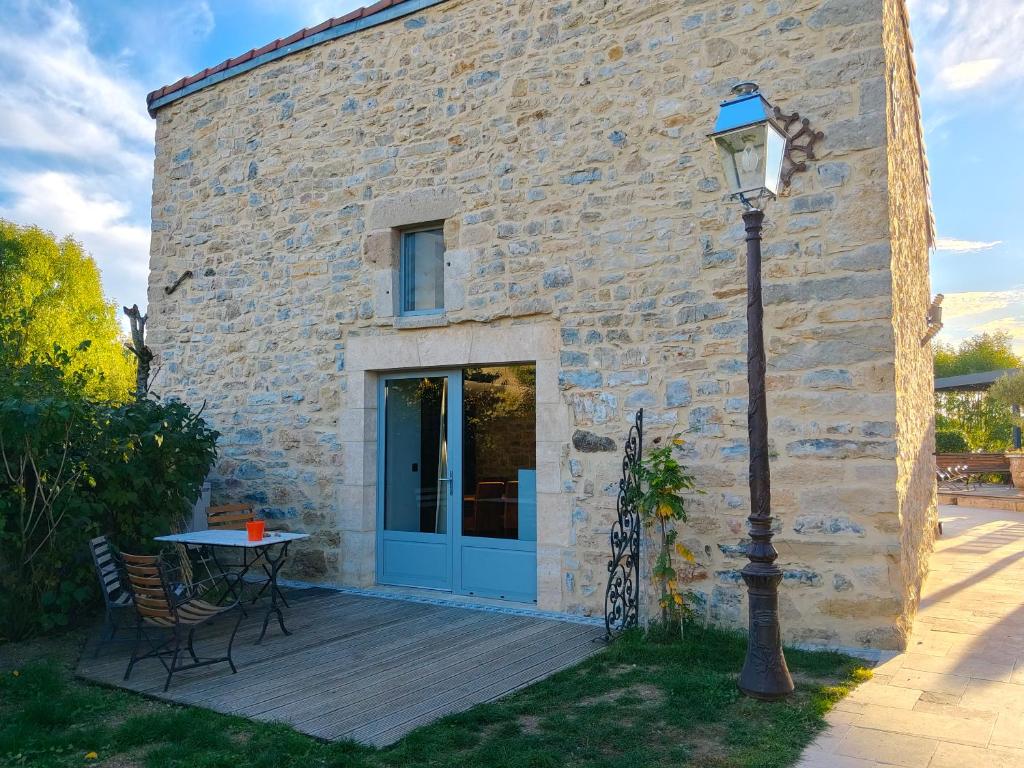 a stone house with a table and a light pole at Gîte du Volcan des Causses in Saint-Jean-dʼAlcapiès