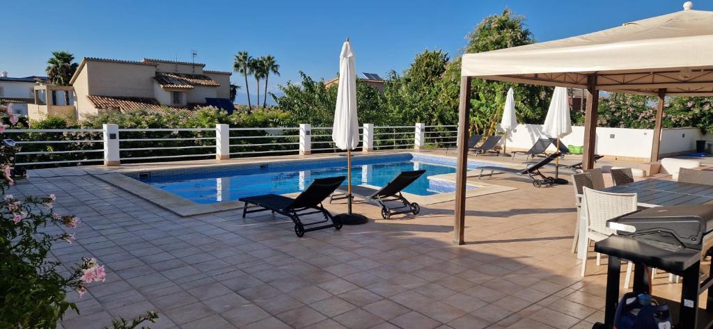 a pool with chairs and umbrellas next to a fence at Finca Ca Nostra, Charmante Villa, Großzügiger Pool & Meerblick in Llucmajor