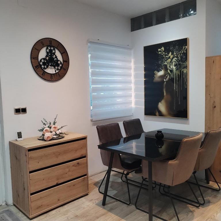 a dining room with a table and chairs and a clock at ForRest Spa Apartment - Private Jacuzzi & Sauna in Ravna Gora