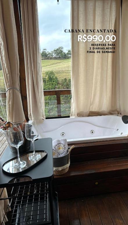 a bath tub with two wine glasses on a table at Cabanas nascer do sol - Encantada in Alfredo Wagner