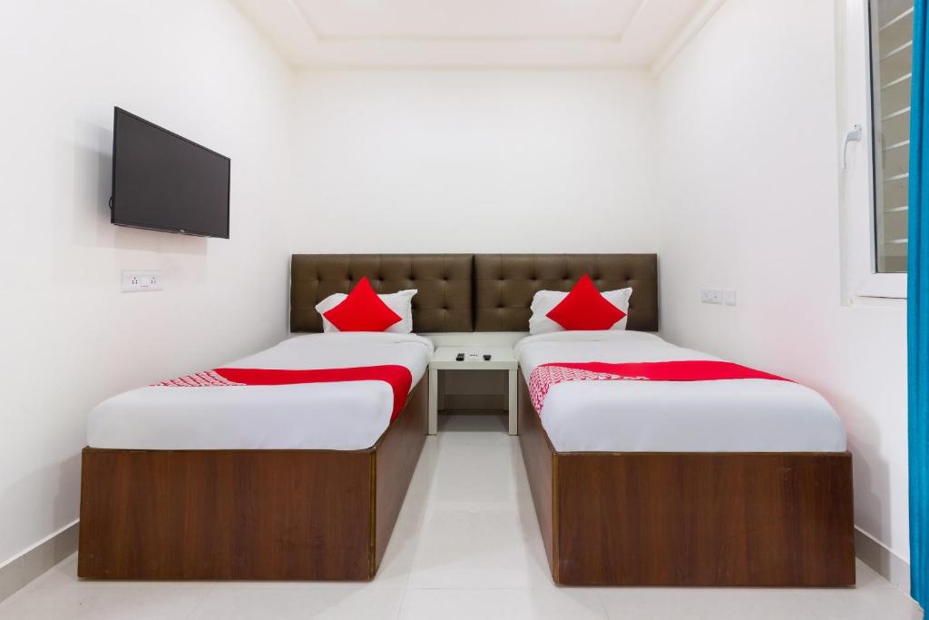 two beds with red pillows in a room at Hotel O Qualia Inn Kondapur Near Botanical Garden in Hyderabad