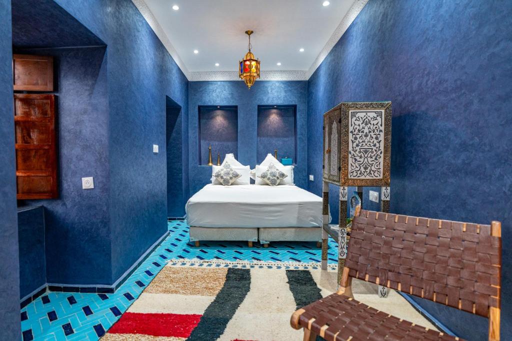 a blue bedroom with a bed and a bench at Riad Serendip in Marrakech