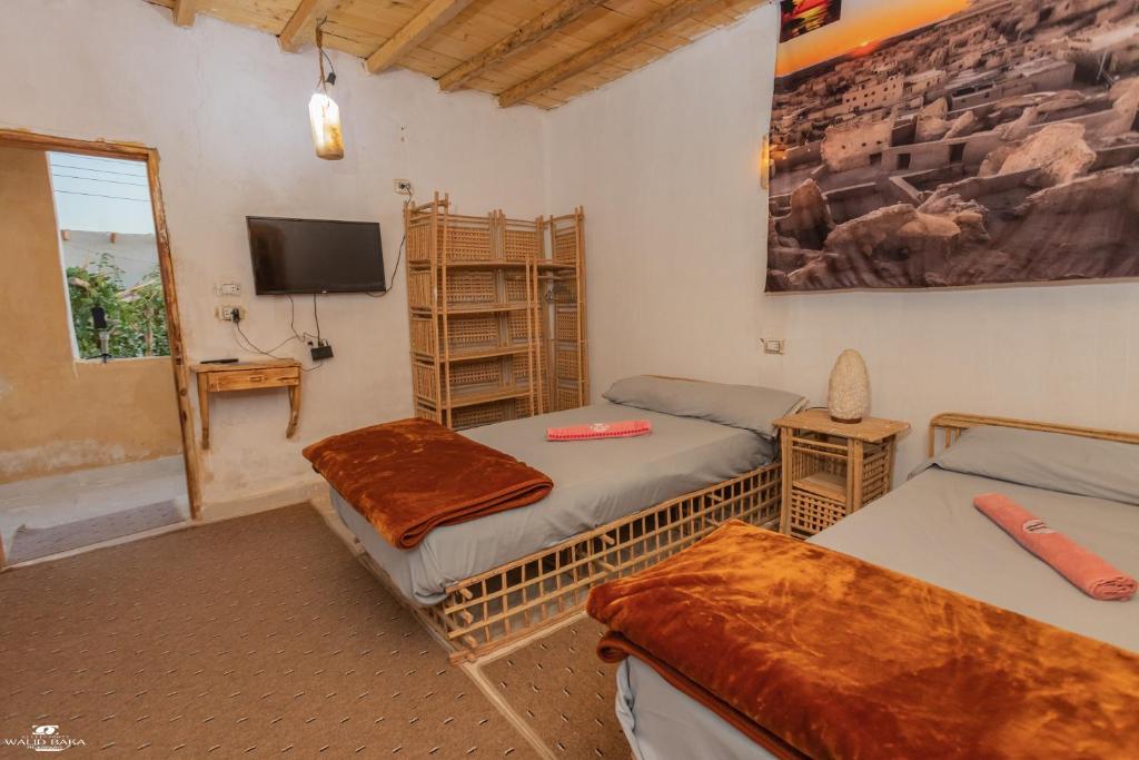 a room with two beds and a tv on the wall at Gagal House in Siwa