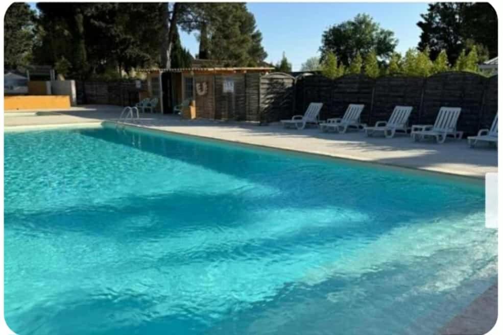 a swimming pool with blue water and white chairs at Mobil-home 5 personnes à louer in Villeneuve-lès-Maguelonne