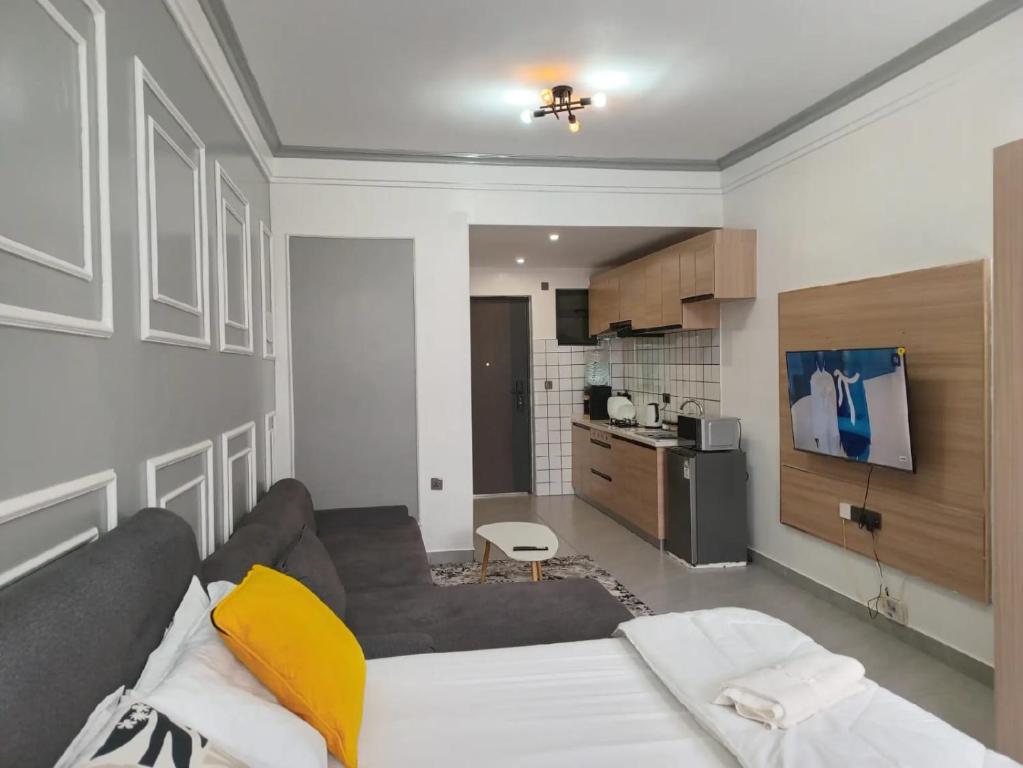 Una sala de estar con un sofá y una cocina. en Lester's Luxe Studio Apartment 15 Minutes from United Nations, en Ruaka