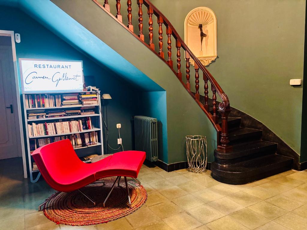 Una escalera con una silla roja y una estantería con libros. en Carmen Guillemot, en Alcanar