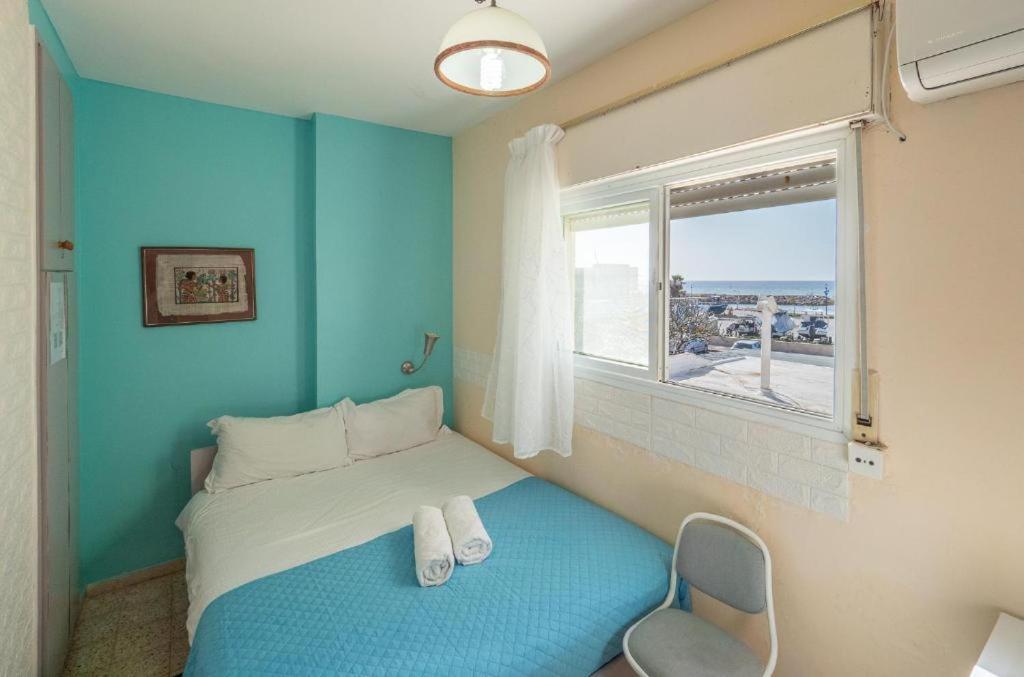 a blue room with a bed and a window at Breezot Yam in Nahariyya