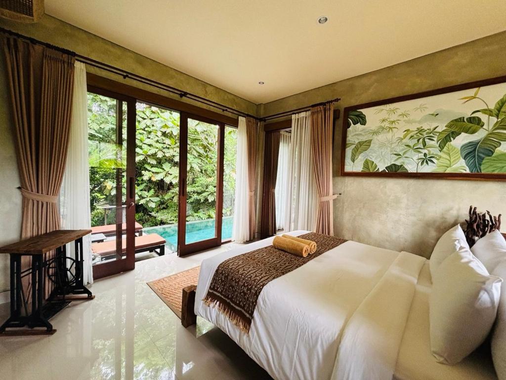 a bedroom with a large bed and large windows at ELForest ex Karang Dukuh Villa, Ubud in Payangan