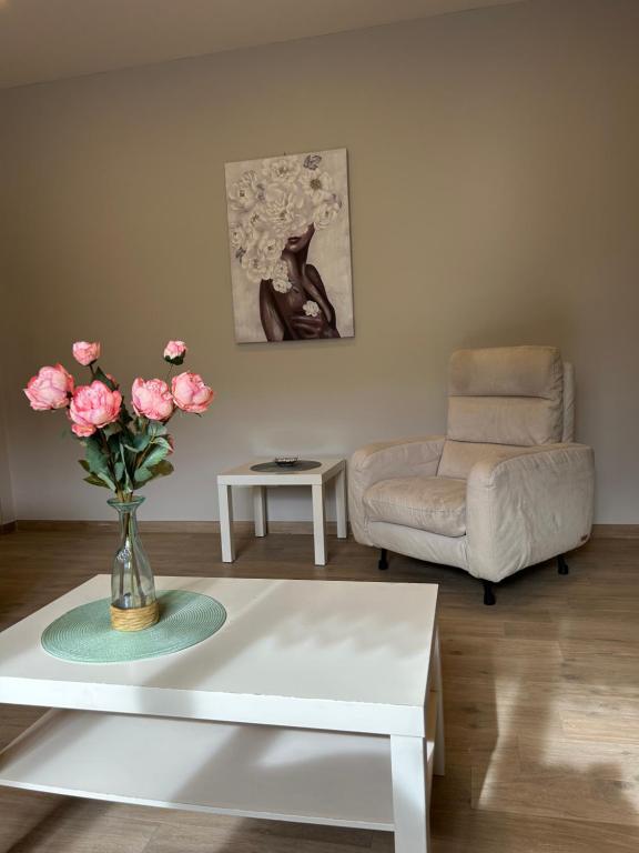 a living room with a table with a vase of pink roses at Viale Apartment in Isola del Liri