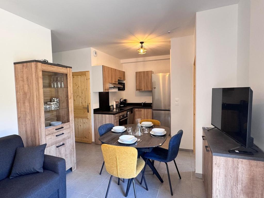 eine Küche und ein Esszimmer mit Tisch und Stühlen in der Unterkunft Appartement neuf T3 avec jardin au bord du lac in Génos