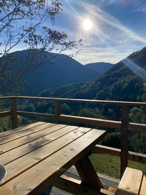 a wooden picnic table on a balcony with a view of mountains at Chalet typique des Pyrénées in Boutx