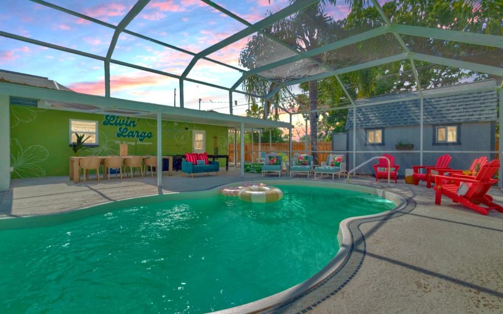 a swimming pool in a yard with red chairs and tables at Breezy Pineapple, Heated Pool, Sleeps 12, Putting Green in Largo
