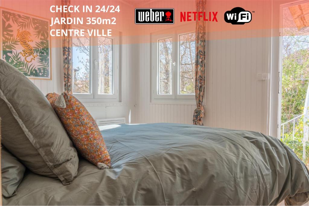 a bed in a room with windows and avertisement at Appartement T3 63m2 - L'Atypique et son Jardin de 350m2 au cœur de Digne in Digne-les-Bains