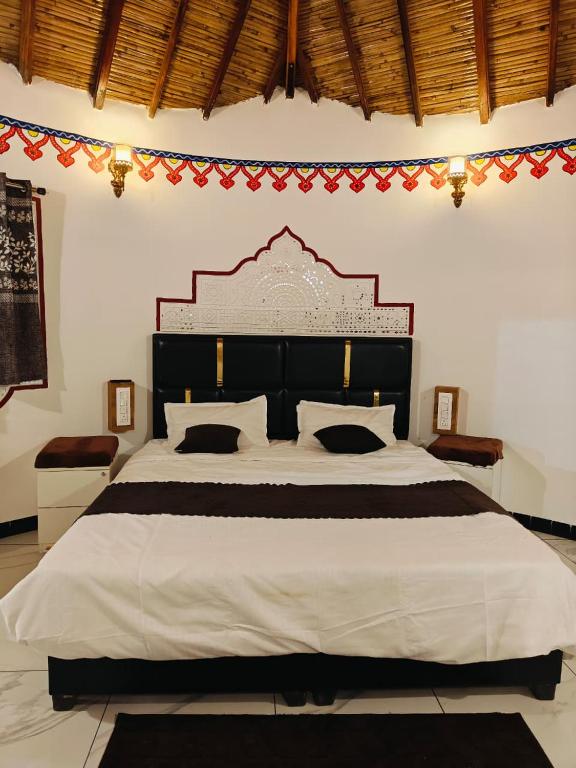 a bedroom with a large white bed with a large headboard at Dholavira Desert Homestay in Dholovira