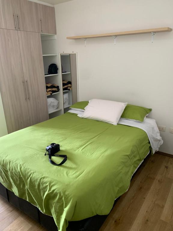 ein Schlafzimmer mit einem grünen Bett mit einer Kamera darauf in der Unterkunft Cómodo monoambiente en El Prado in Cochabamba