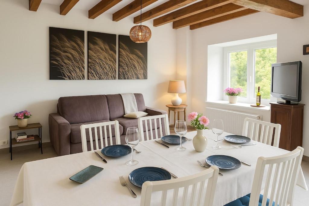 a dining room with a table and a couch at La longère des cerisiers 