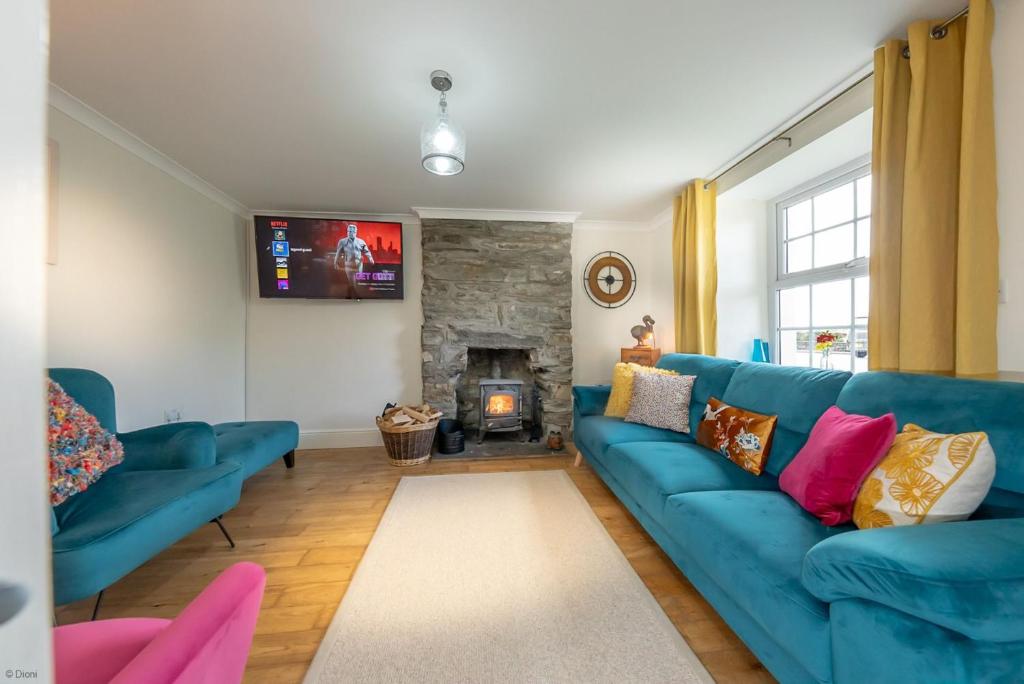 Una sala de estar con un sofá azul y una chimenea. en Isgoed, en Talsarnau