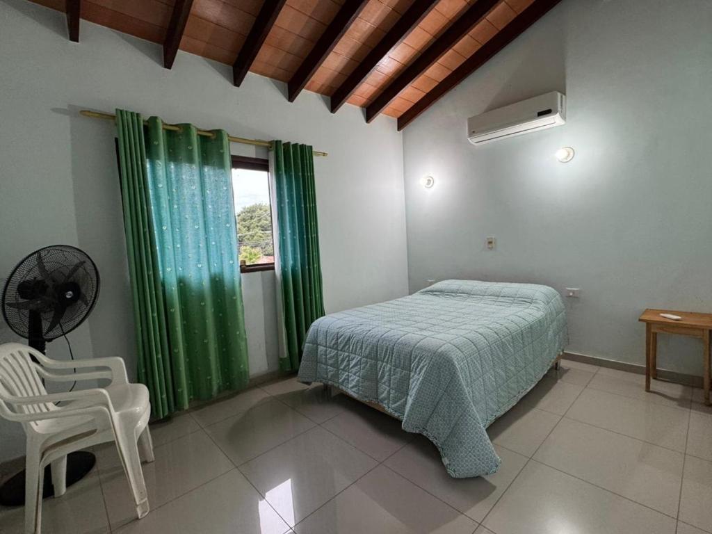 a bedroom with a bed and a chair and a window at Residencia Las Marías in Pilar