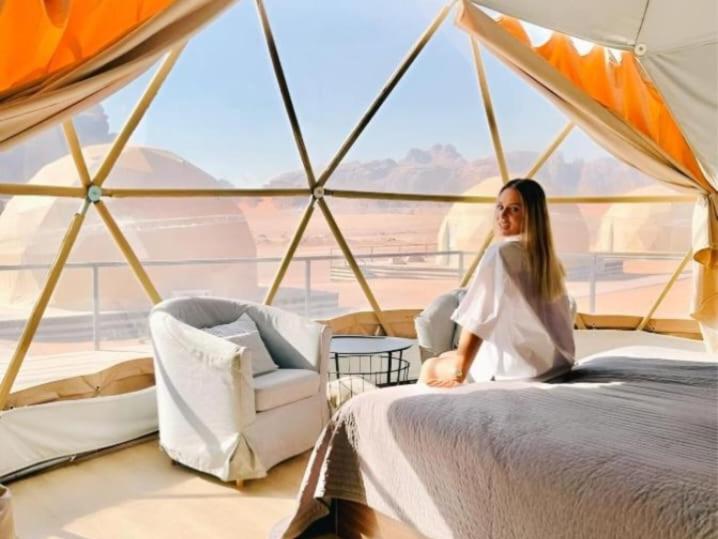 a woman sitting on a bed in a tent at Wadi Rum March in Aqaba