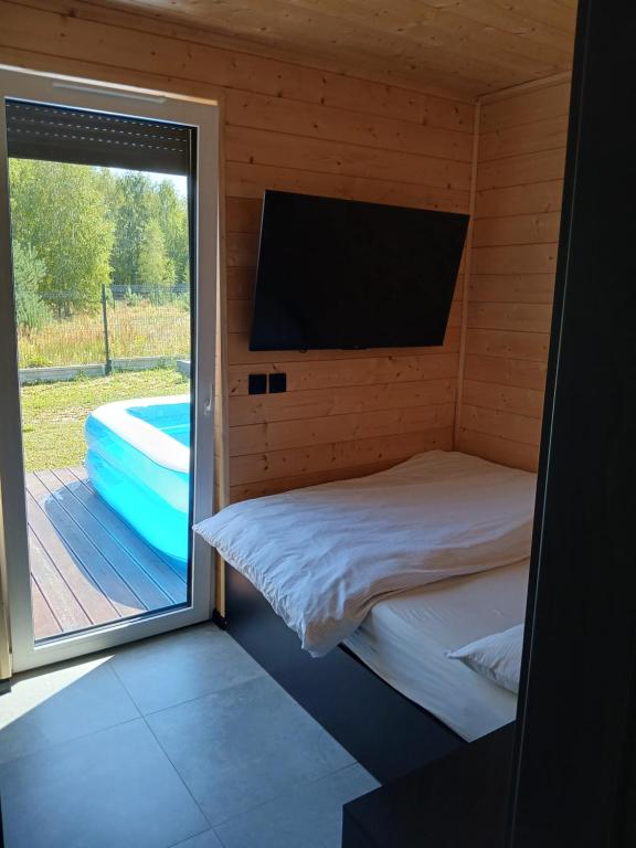 a room with a bed and a window with a tv at Domek nad Jeziorkiem Sauna -Silownia-Balia in Waliska
