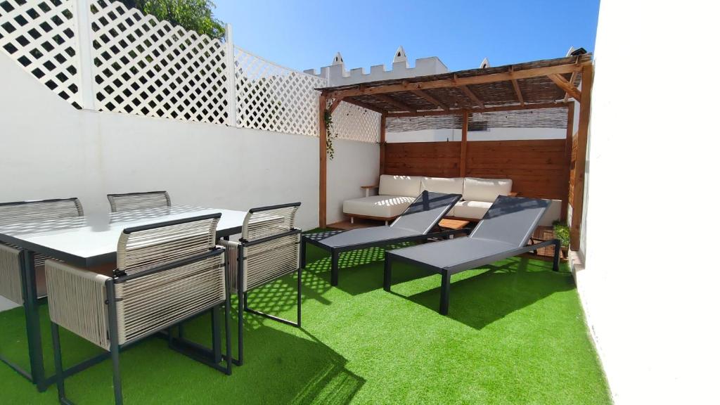 a patio with chairs and a table and grass at Marbella Golf 101 - Bungalow con 2 dormitorios en Maspalomas in Maspalomas