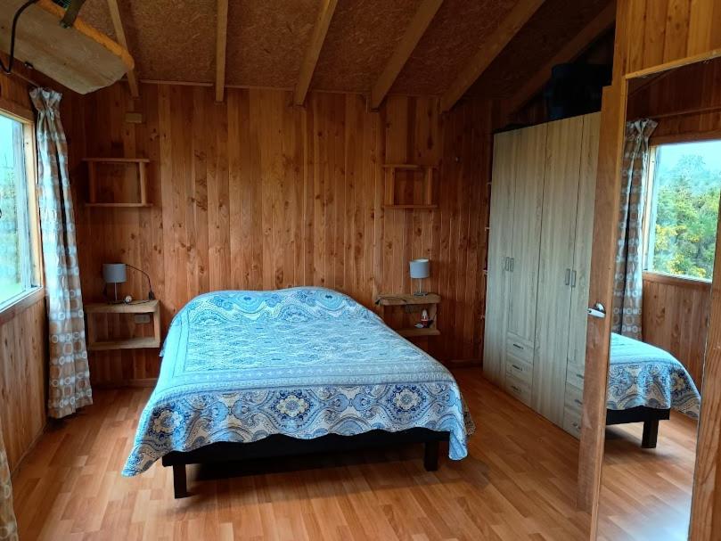 a bedroom with a bed in a wooden room at Casa de Campo in Ancud