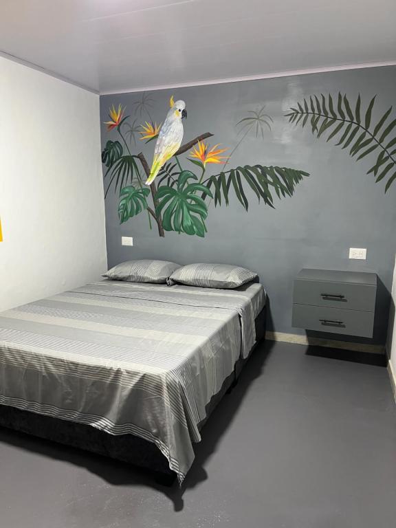 a bedroom with a bed with a bird on the wall at Alojamiento Rural Cafetero, Andinapolis, Trujillo 