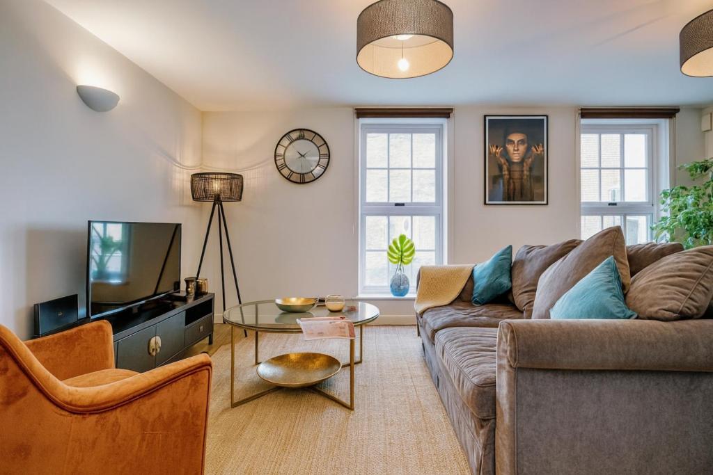 a living room with a couch and a tv at Central Windsor 2 Bed 2 Bath, FREE Parking 300m to Castle, Pet Friendly in Windsor
