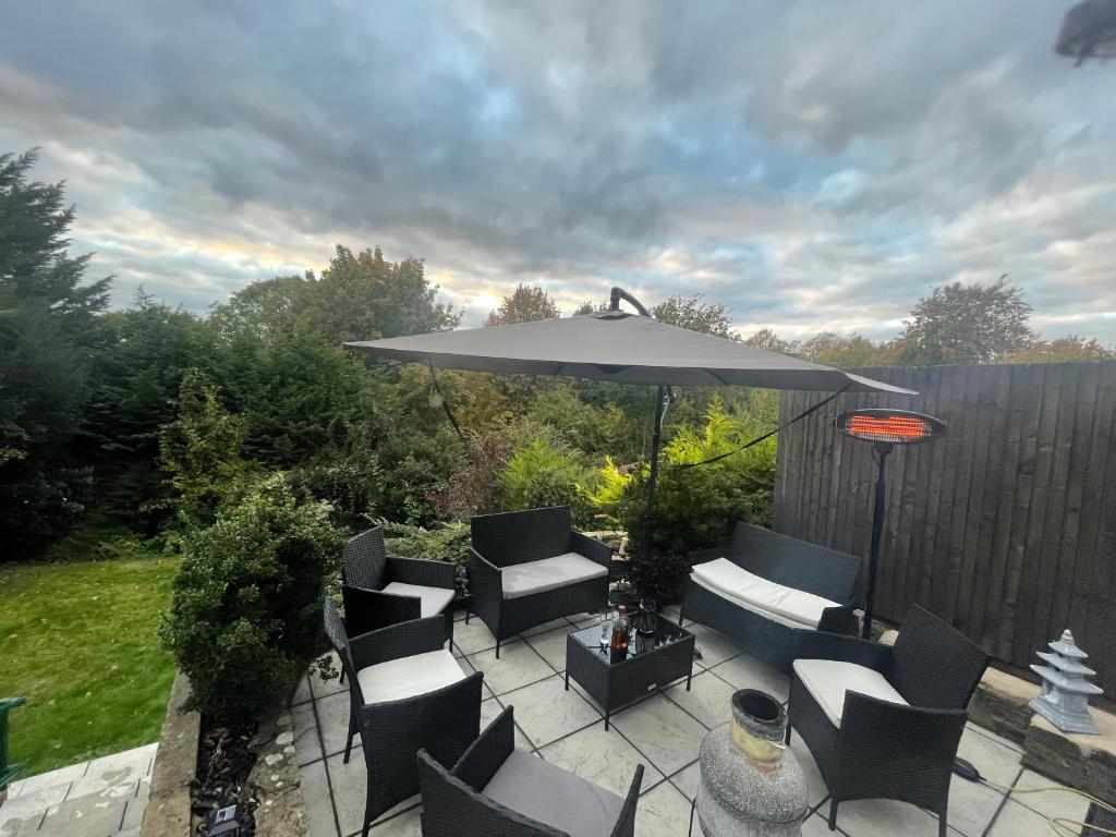 a patio with an umbrella and chairs and a table at The Diamond Retreat in Purley