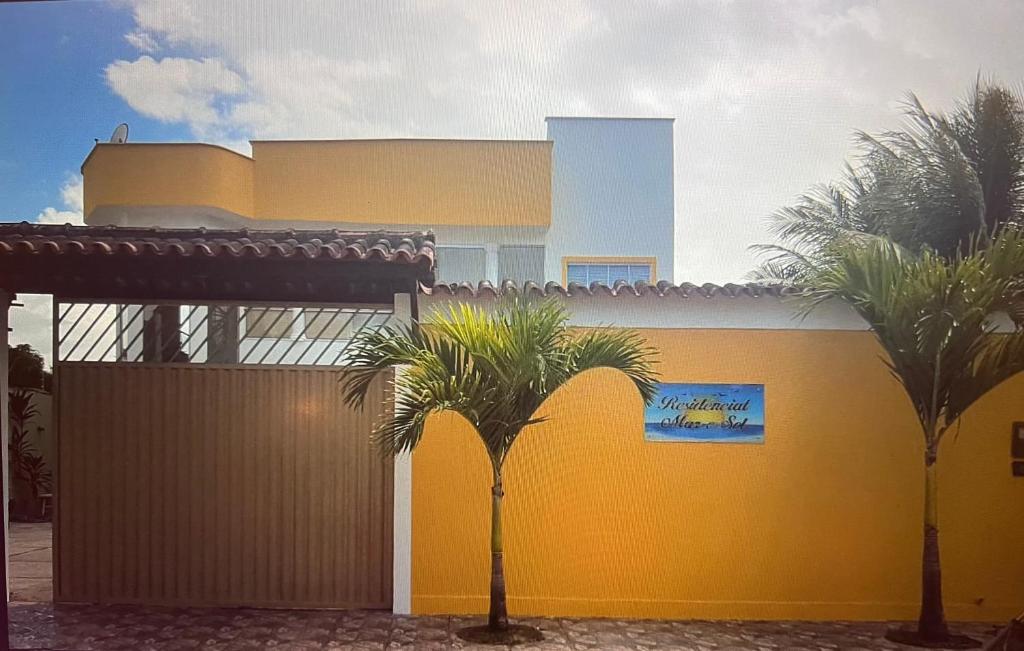 a yellow building with palm trees in front of it at Paraíso Tropical em Porto Seguro in Porto Seguro